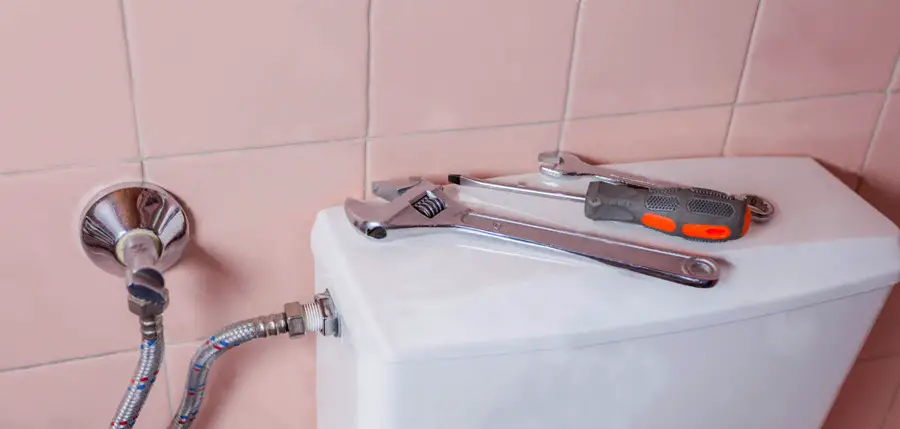 wrench & Screwdriver put on Toilet Tank Lid Cover, background tiles color pink